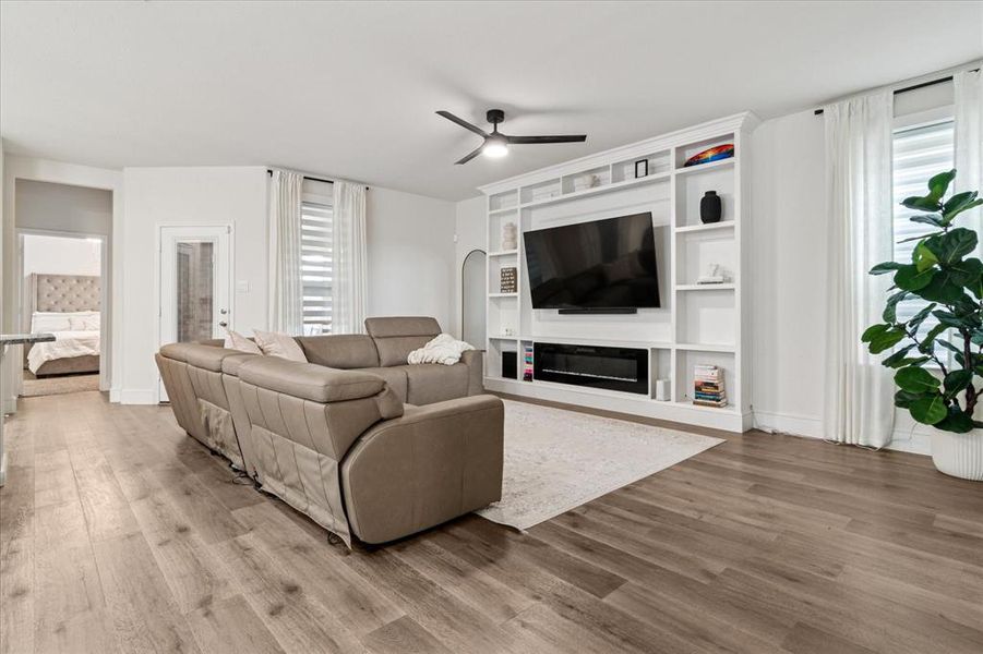 Living area featuring ceiling fan, wood finished floors, and a glass covered fireplace Living area featuring ceiling fan, wood finished floors, and a glass covered fireplace