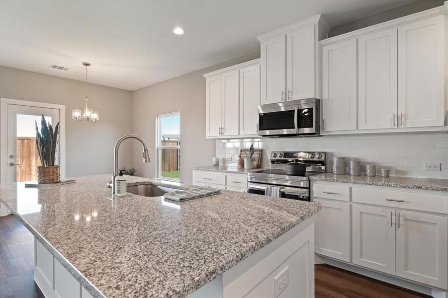 Kitchen with stainless steel appliances, a kitchen island with sink, and dark wood-type flooring Kitchen with stainless steel appliances, a kitchen island with sink, and dark wood-type flooring