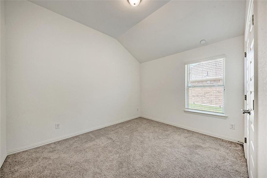 A well-lit room showcases plush carpeting and vaulted ceilings, creating an inviting atmosphere.
