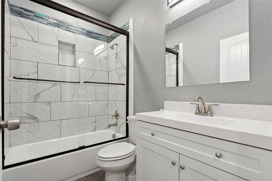 Full bathroom with shower / bath combination with glass door, toilet, and vanity