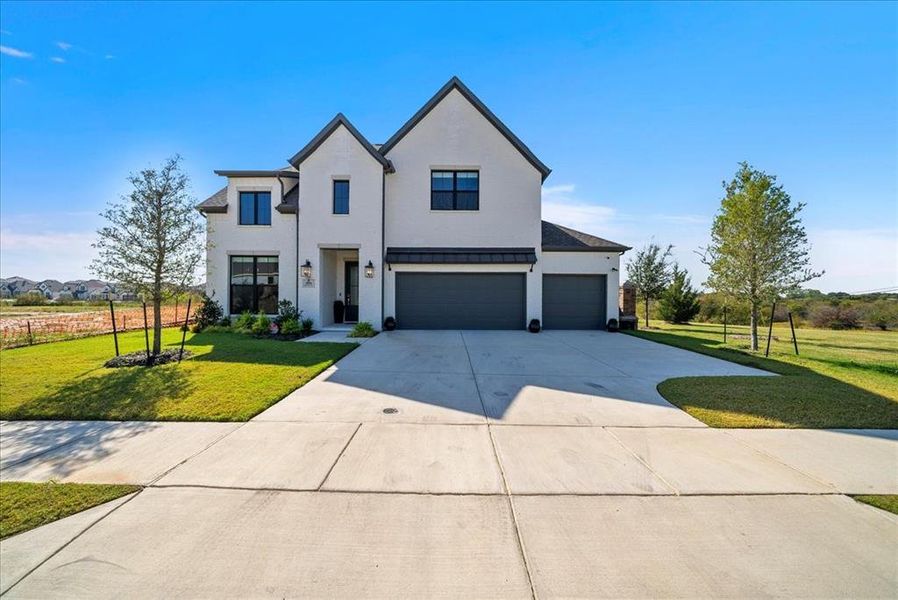 Modern inspired farmhouse with a garage, driveway, a standing seam roof, and a front yard