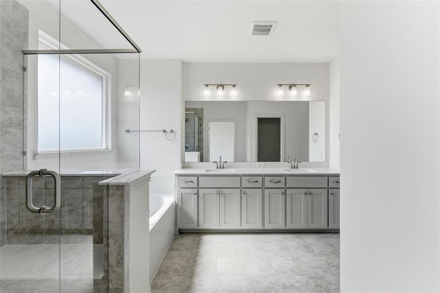 Full bath with a shower stall, double vanity, and a garden tub