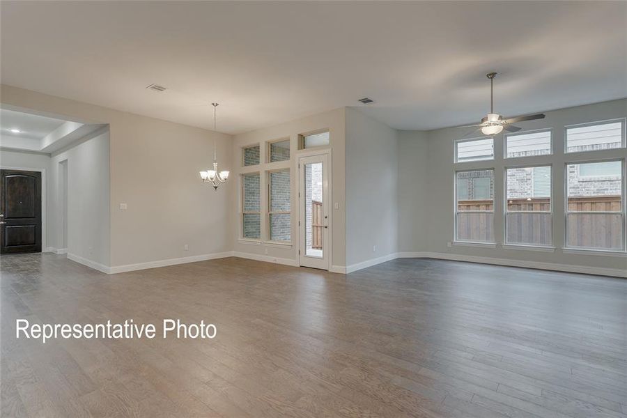 Unfurnished room with ceiling fan with notable chandelier and hardwood / wood-style floors