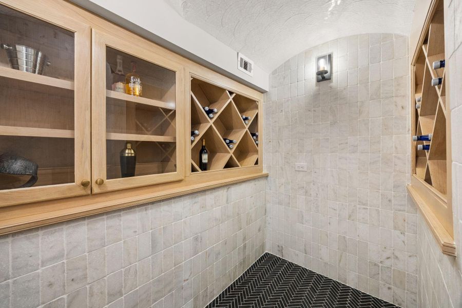 Temp controlled wine room is tiled w/ tumbled travertine and offers custom site-built wine storage.