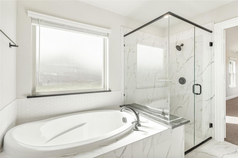 Master bathroom with soaking tub and glass-enclosed shower featuring marble tile walls Master bathroom with soaking tub and glass-enclosed shower featuring marble tile walls