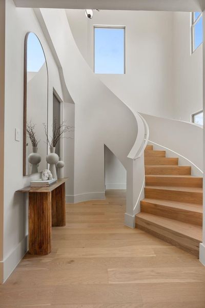 A grand first impression, the sculptural staircase with integrated linear lighting and 20-ft ceiling set the tone for the thoughtfully curated interior. A grand first impression, the sculptural staircase with integrated linear lighting and 20-ft ceiling set the tone for the thoughtfully curated interior.