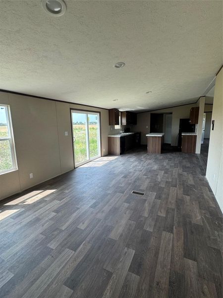 Sliding glass doors open to the outdoors, illuminating the wood-look flooring and open floorplan.