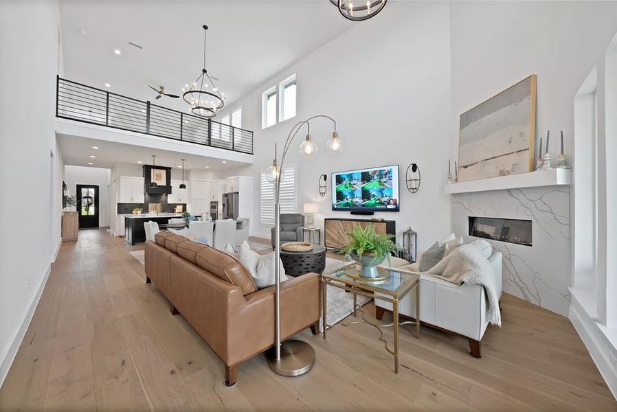 Great room featuring high ceilings, wood-finish flooring, and a linear fireplace with a stone surround Great room featuring high ceilings, wood-finish flooring, and a linear fireplace with a stone surround