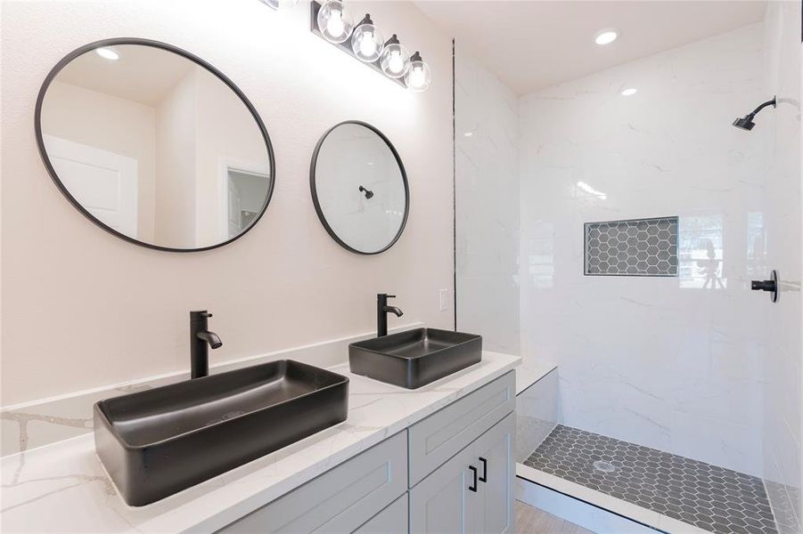 Bathroom featuring a tile shower and vanity