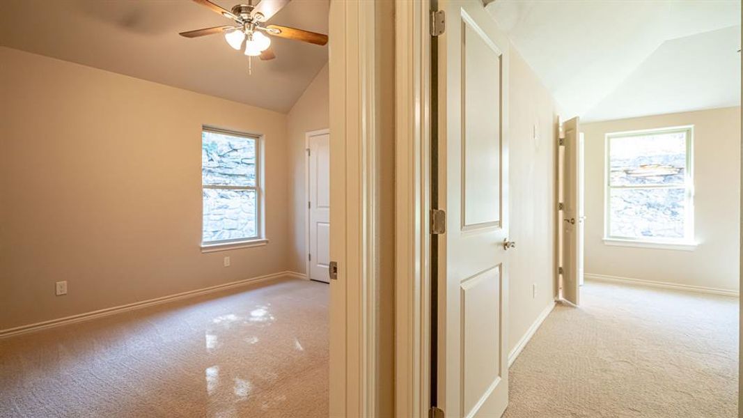 Hallway with lofted ceiling and light colored carpet