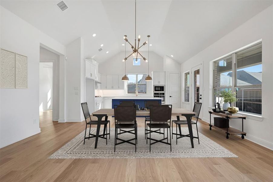 Dining area featuring suspended lighting, light wood-type flooring, and lofted ceiling Dining area featuring suspended lighting, light wood-type flooring, and lofted ceiling