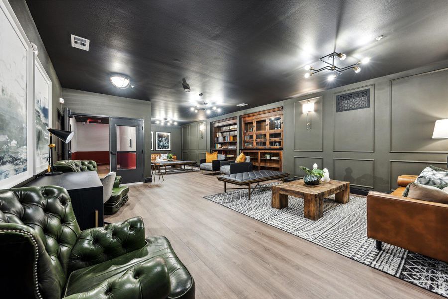 An inviting gathering area with built-in shelving, rich wood flooring, and modern lighting offers comfortable seating. An inviting gathering area with built-in shelving, rich wood flooring, and modern lighting offers comfortable seating.