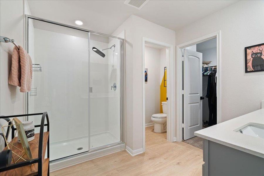 Bathroom featuring visible vents, a shower stall, toilet, wood finished floors, and a walk in closet