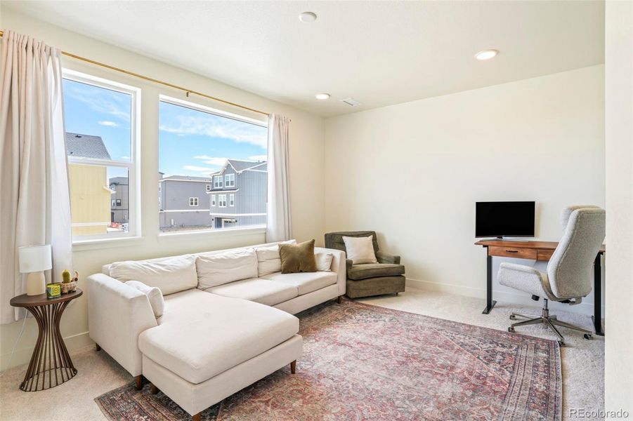 Light-filled loft space perfect for a second living area, home office, or flex space in this thoughtfully designed Three Hills home