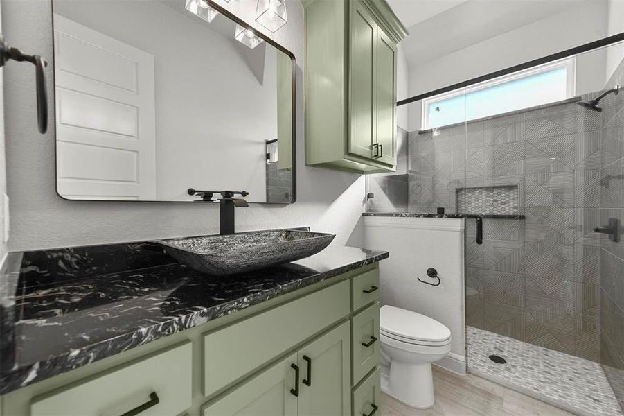 Bathroom featuring tiled shower, vanity, hardwood / wood-style flooring, and toilet