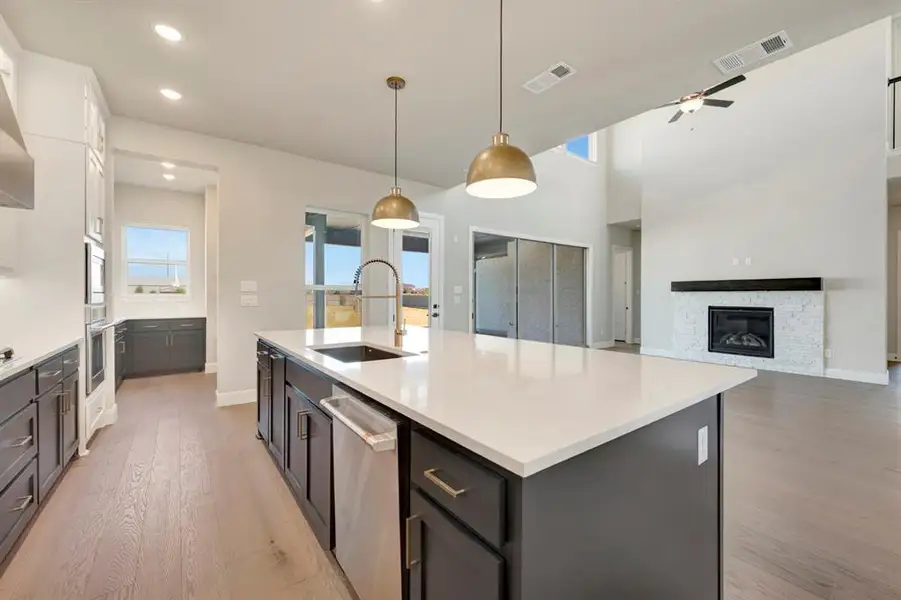 Dual tone kitchen featuring decorative light fixtures, light wood-type flooring, stainless steel appliances, healthy amount of natural light, and dual tone cabinetry Dual tone kitchen featuring decorative light fixtures, light wood-type flooring, stainless steel appliances, healthy amount of natural light, and dual tone cabinetry
