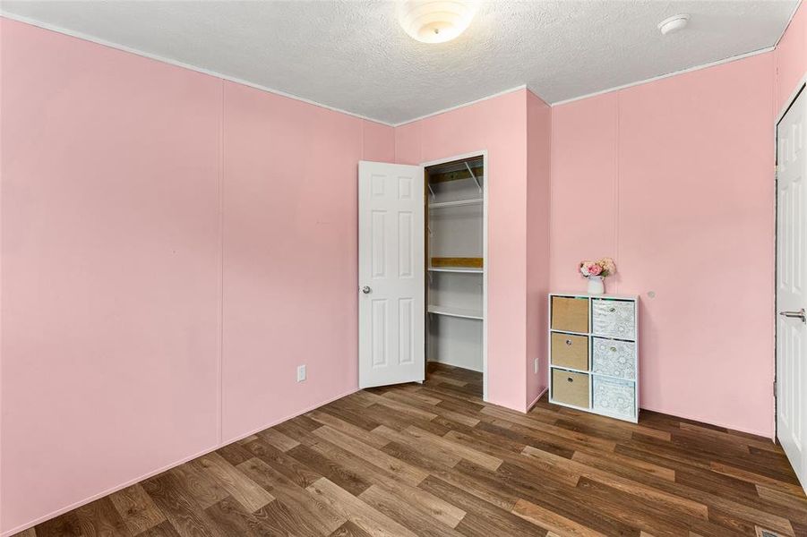 Unfurnished bedroom with dark wood-type flooring, a textured ceiling, and a closet