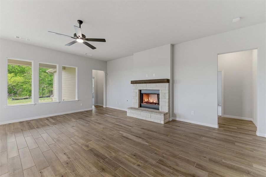 Unfurnished living room featuring a ceiling fan, a fireplace, and light wood-style floors