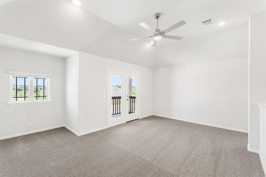 Empty room with vaulted ceiling, ceiling fan, carpet flooring, and French doors leading to a balcony