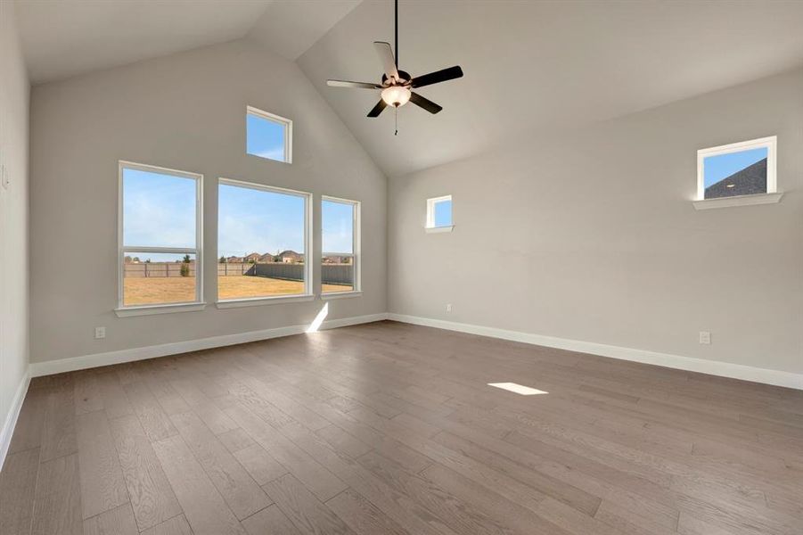 Empty room featuring a high ceiling, a ceiling fan, and dark wood finished floors Empty room featuring a high ceiling, a ceiling fan, and dark wood finished floors