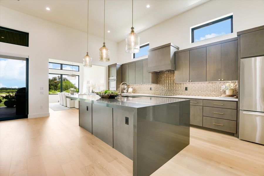 A grand, modern kitchen with a waterfall island flows seamlessly into an airy dining area.