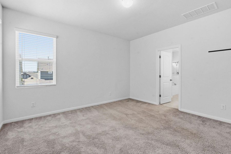 A well-lit bedroom features plush carpeting and a convenient en-suite bathroom. A well-lit bedroom features plush carpeting and a convenient en-suite bathroom.