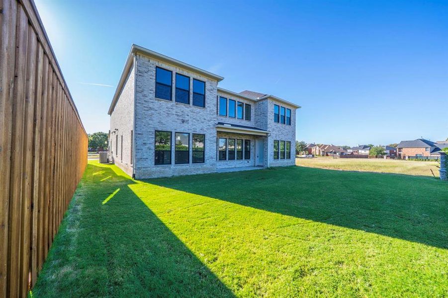 Rear view of property featuring brick siding, a yard, and a patio area Rear view of property featuring brick siding, a yard, and a patio area