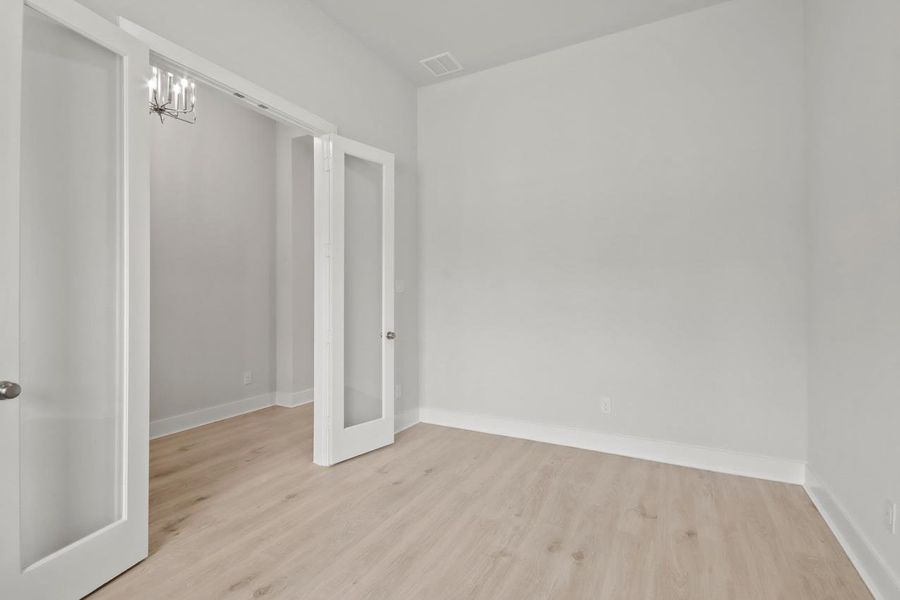 Empty room featuring baseboards, wood finished floors, and a notable chandelier Empty room featuring baseboards, wood finished floors, and a notable chandelier