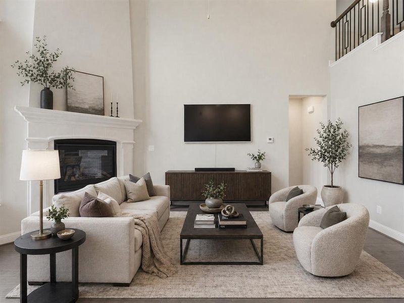 Spacious living area featuring a two-story ceiling, elegant fireplace with a substantial mantel, dark wood-finish flooring, and an open balcony with decorative railings