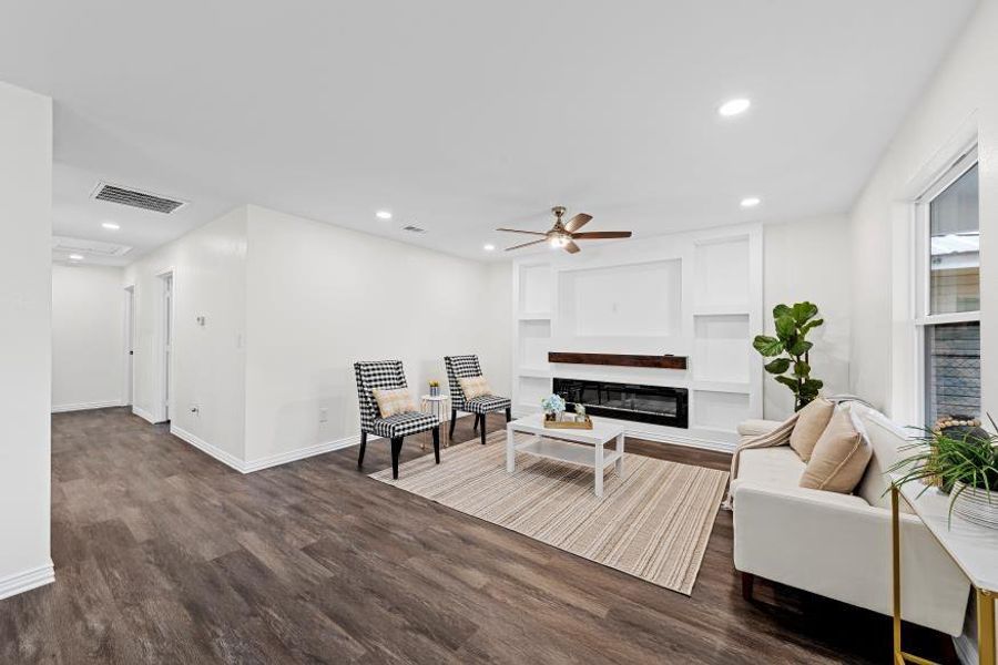Living room featuring a ceiling fan, dark wood-style floors, built in features, recessed lighting, and a glass covered fireplace Living room featuring a ceiling fan, dark wood-style floors, built in features, recessed lighting, and a glass covered fireplace