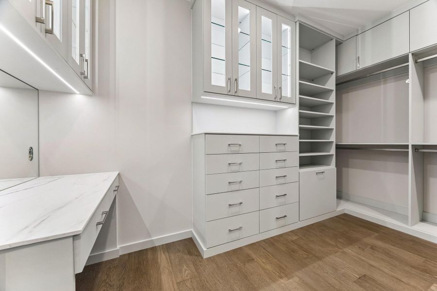 You will certainly enjoy this custom-built upgraded primary dressing room. It features bespoke built-ins, a dedicated make-up vanity with wall sconces, floor to ceiling upper glass front cabinets illuminated with integrated lighing.