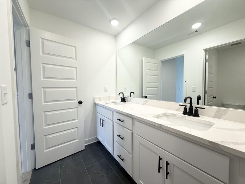 Full bath with double vanity, recessed lighting, and dark tile patterned flooring