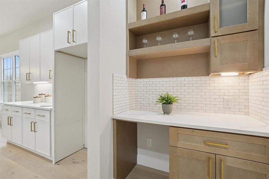 featuring decorative backsplash, light wood-style flooring, open shelves, and light stone counters