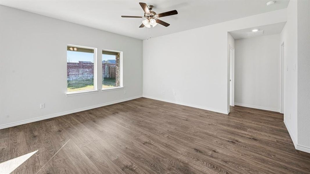 This room features wood-look flooring, light-colored walls, and two windows providing natural light