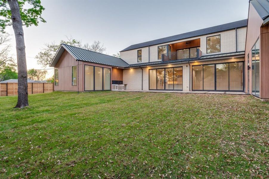 Expansive glass and thoughtful design create a seamless connection to the backyard, while the balcony above offers an elevated outdoor retreat.