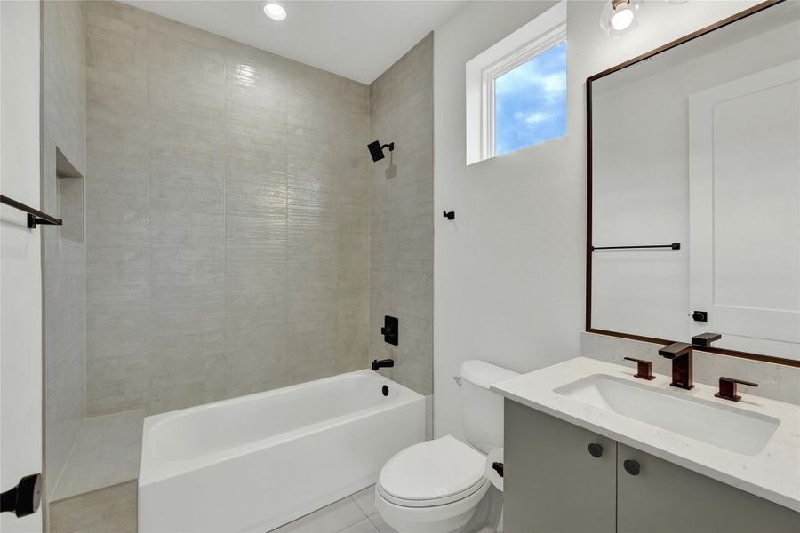 Bathroom featuring vanity, tub / shower combination, light tile patterned floors, and recessed lighting