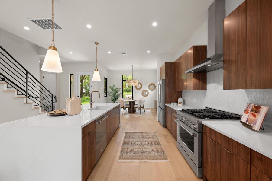 A sleek, contemporary kitchen boasts light wood flooring and stainless steel appliances, flowing into a casual dining area. A sleek, contemporary kitchen boasts light wood flooring and stainless steel appliances, flowing into a casual dining area.