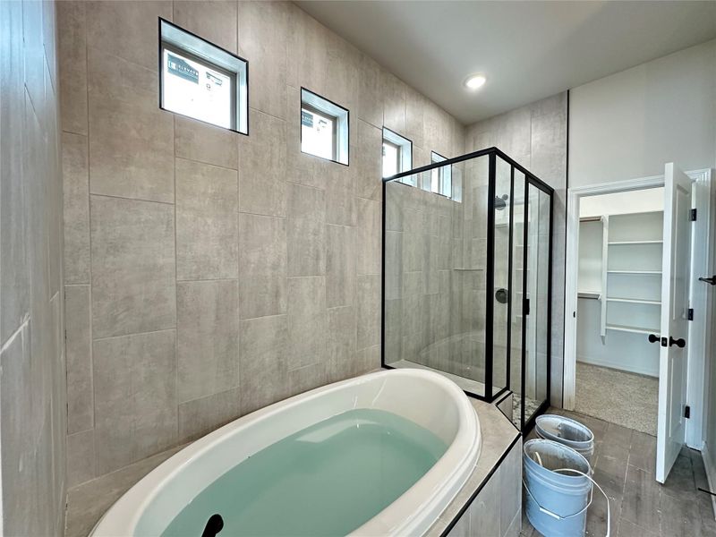 Bathroom featuring a spacious closet, a stall shower, and a bath