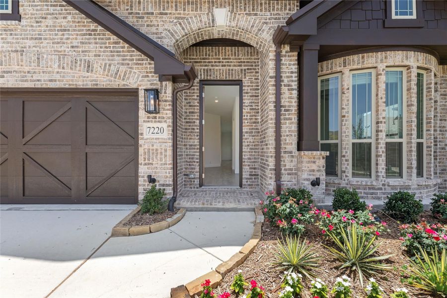Brick home exterior with arched front entry, single-car garage, and landscaped flower beds Brick home exterior with arched front entry, single-car garage, and landscaped flower beds