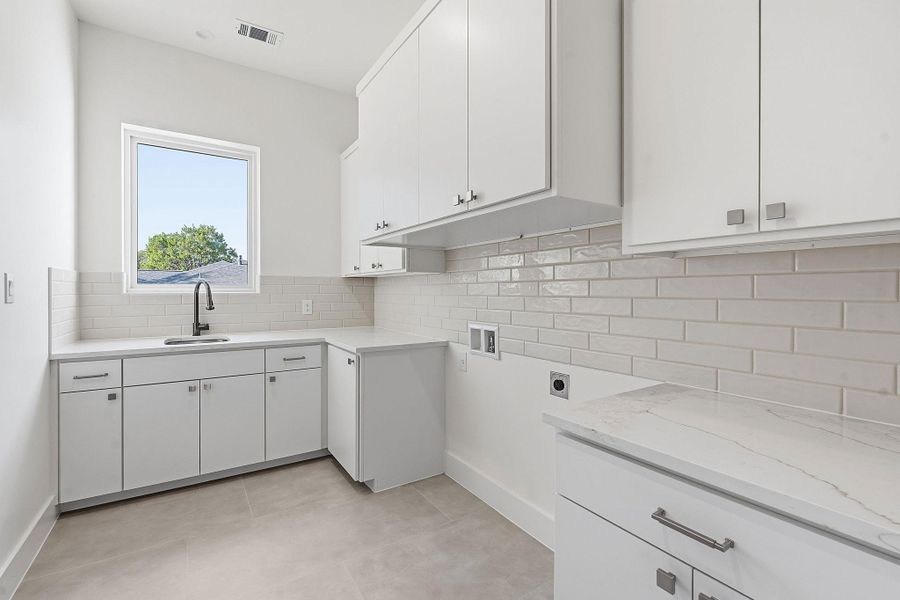 Streamlined cabinetry and sleek countertops define this modern, highly functional utility space.