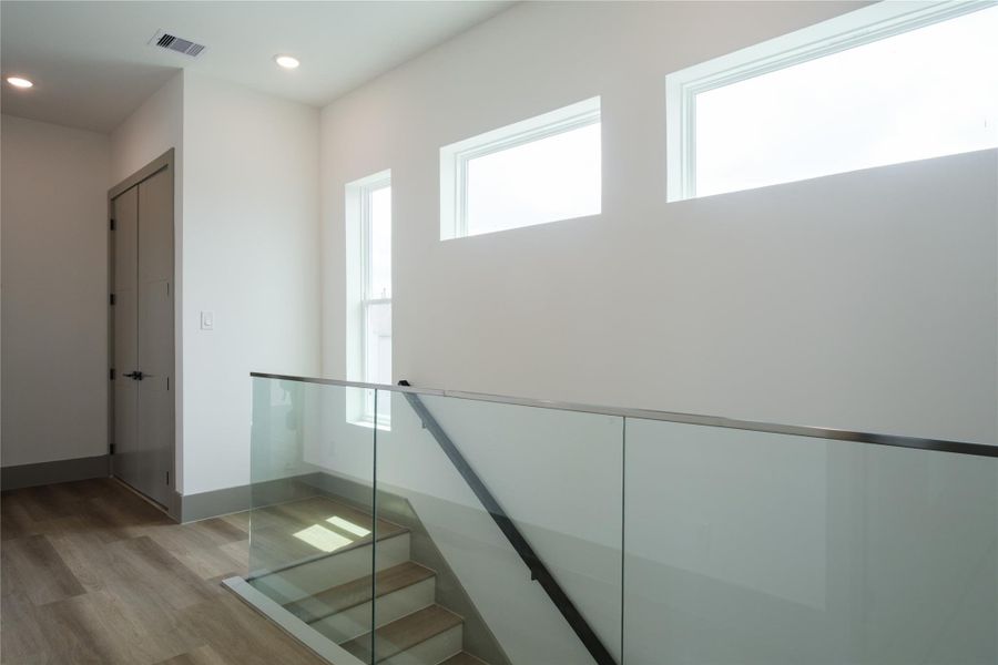 Representative Hallway / Staircase View (Design selections and colors may vary): A transparent glass wall with steel railings gives this hallway a light, open feeling while maintaining safety and adding to the home's architectural appeal.