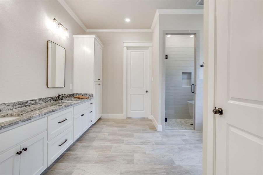 Spacious bathroom featuring a dual vanity with light-toned countertops, white cabinetry, and matte black hardware