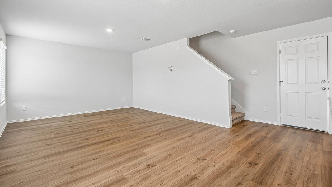 Laminate wood flooring and bright recessed lighting define this inviting open living space.