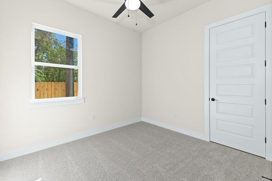 Carpeted empty room with baseboards and ceiling fan