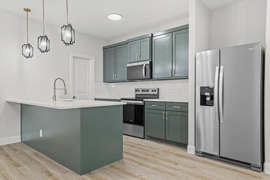 Kitchen with kitchen peninsula, appliances with stainless steel finishes, sink, pendant lighting, and light hardwood / wood-style flooring