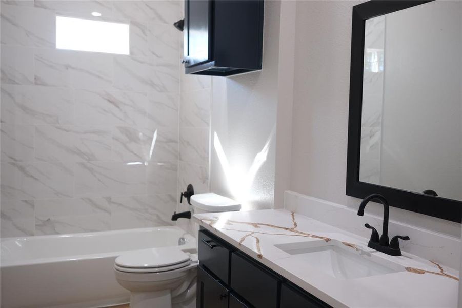 Bathroom with vanity, shower / bath combination, and a textured wall Bathroom with vanity, shower / bath combination, and a textured wall