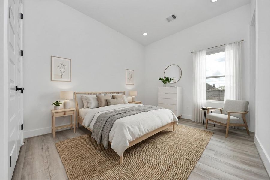 Bright and airy bedroom with modern decor. Features a cozy bed, natural wood furniture, a large window with sheer curtains, and light wood flooring.
