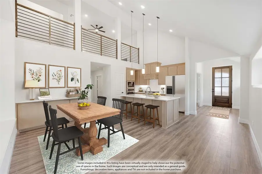 Open-concept dining and kitchen area with two-story ceilings, wood floors, and a large island with bar seating