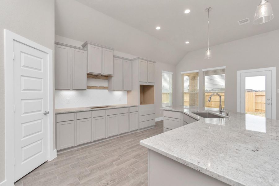 Discover another perspective of this stunning kitchen, generously appointed with an abundance of counter space. Sample photo of completed home with similar floor plan. Actual colors and selections may vary. Discover another perspective of this stunning kitchen, generously appointed with an abundance of counter space. Sample photo of completed home with similar floor plan. Actual colors and selections may vary.