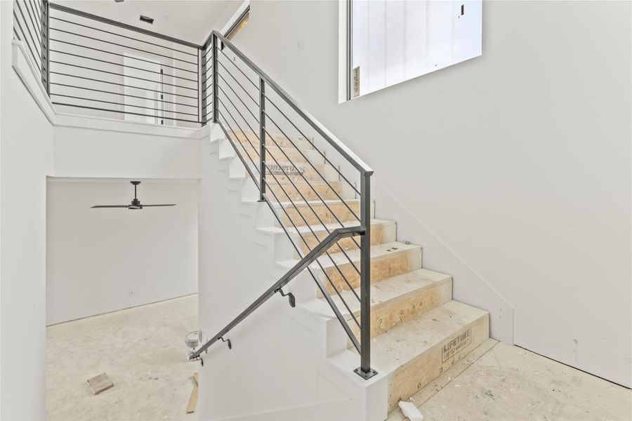 Modern staircase featuring horizontal metal railings and a corresponding handrail